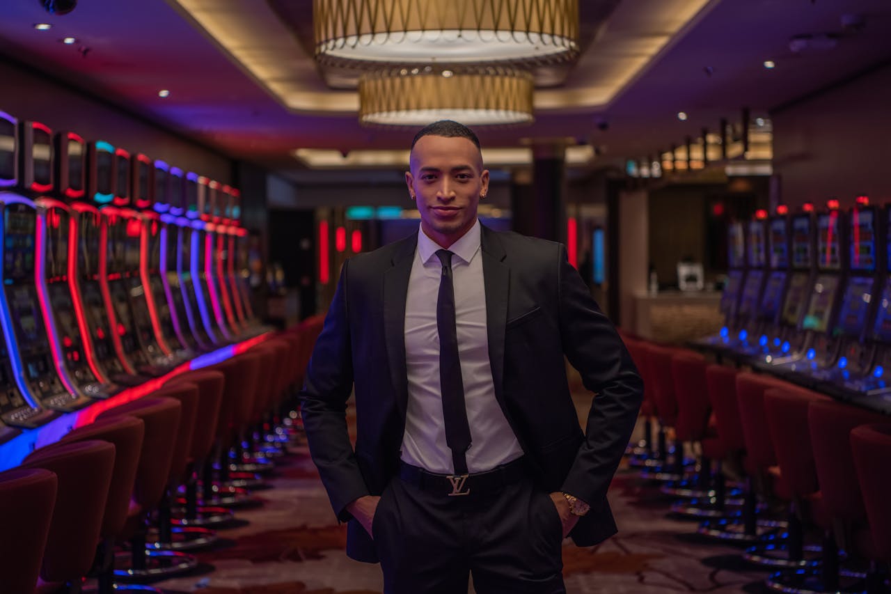 Businessman standing confidently in a luxurious casino with rows of gaming machines.
